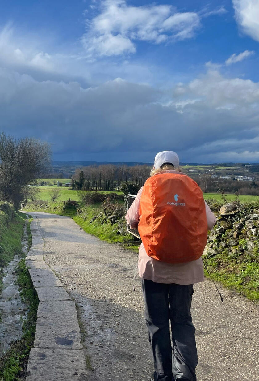 A pilgrim walking the Camino through green countryside